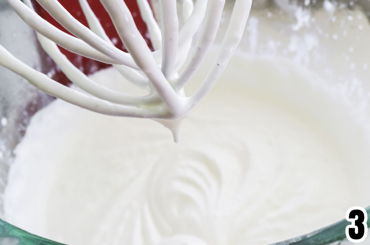 Closeup on a glass mixing bowl filled with whipping cream whipped to soft peaks.