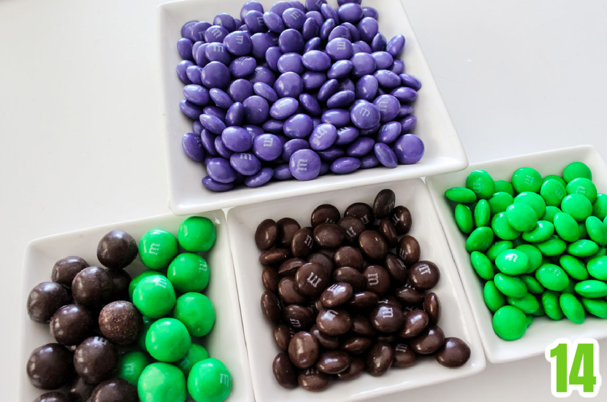 Four white ramekins filled with green, brown, and purple M&M's.