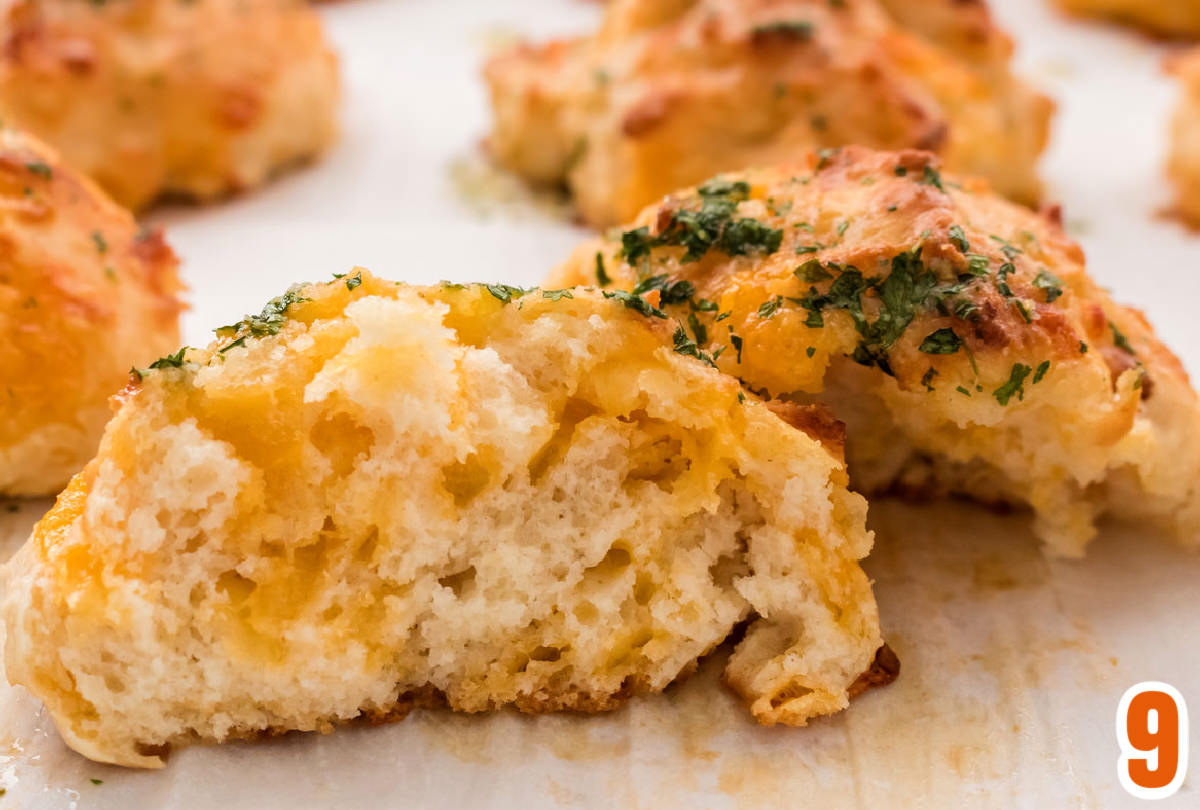 A Cheddar Bay Biscuit cut in half showing the melty cheese inside.