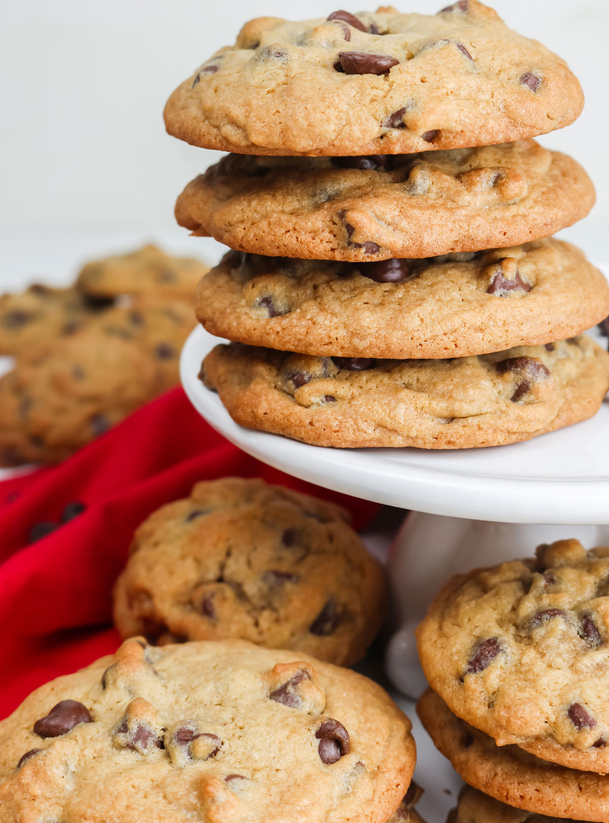 Closeup on a white cake stand covered with stacks of Chocolate Chip Cookies.