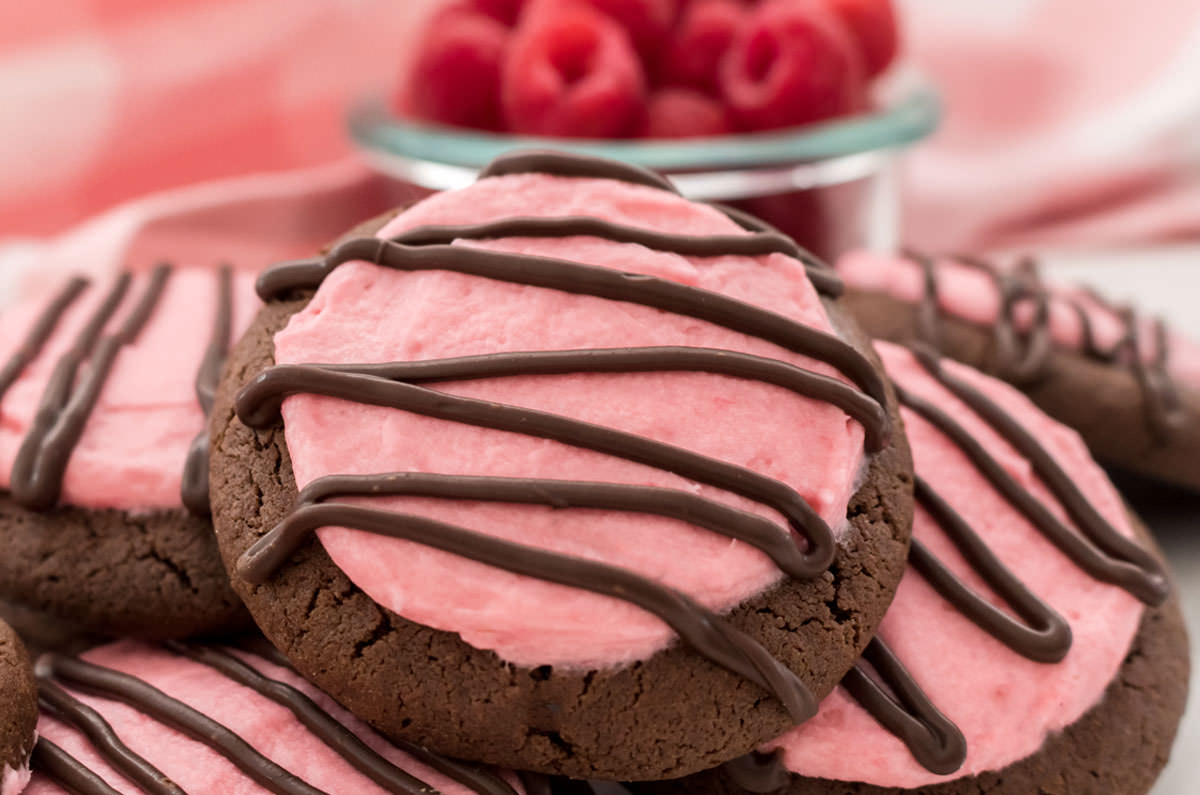 Close up of a Chocolate Cookie frosted with homemade Raspberry Frosting and decorated with a drizzle of melted chocolate.