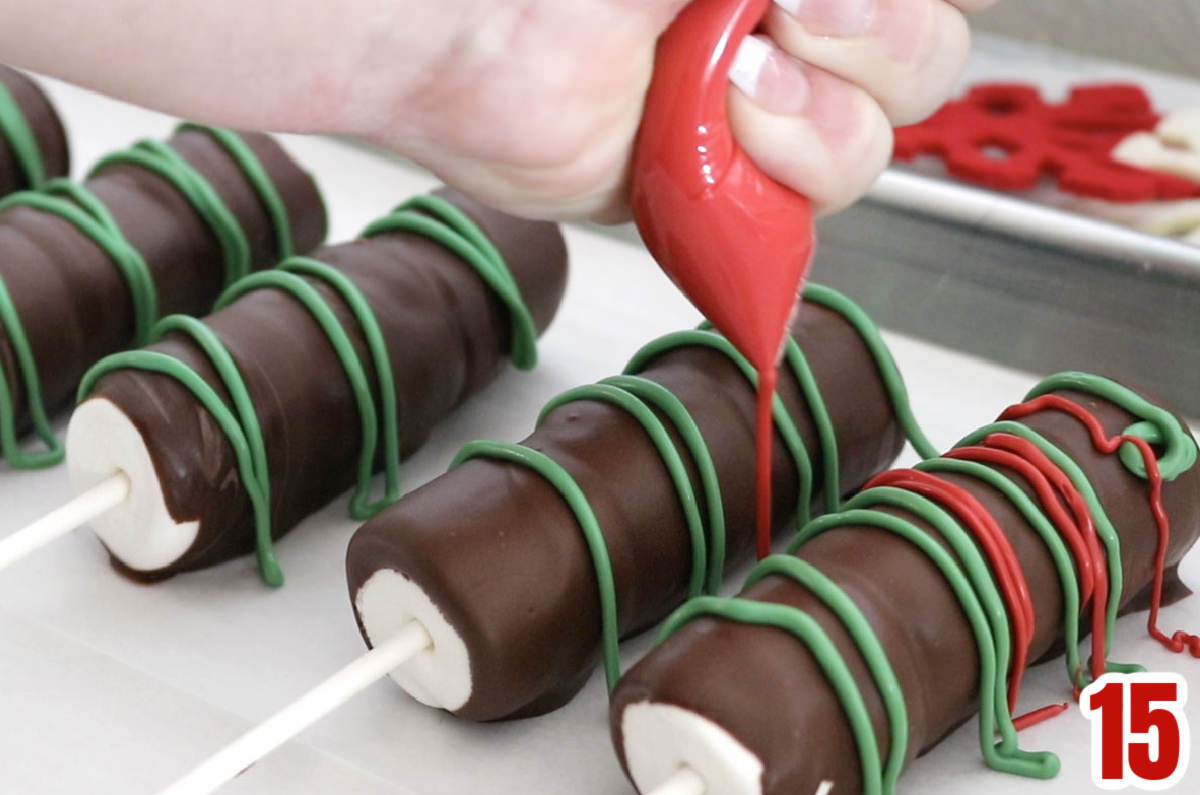 Five undecorated Marshmallow Pops being drizzled with red and green melted Candy Melts.