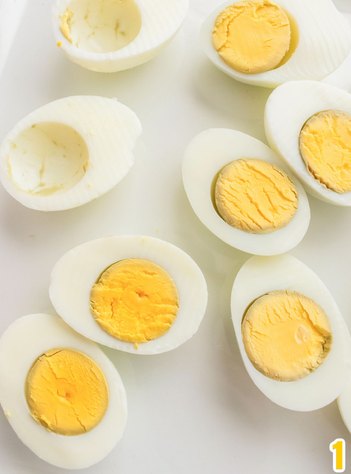 Hardboiled eggs cut in half and laying on a white serving platter.