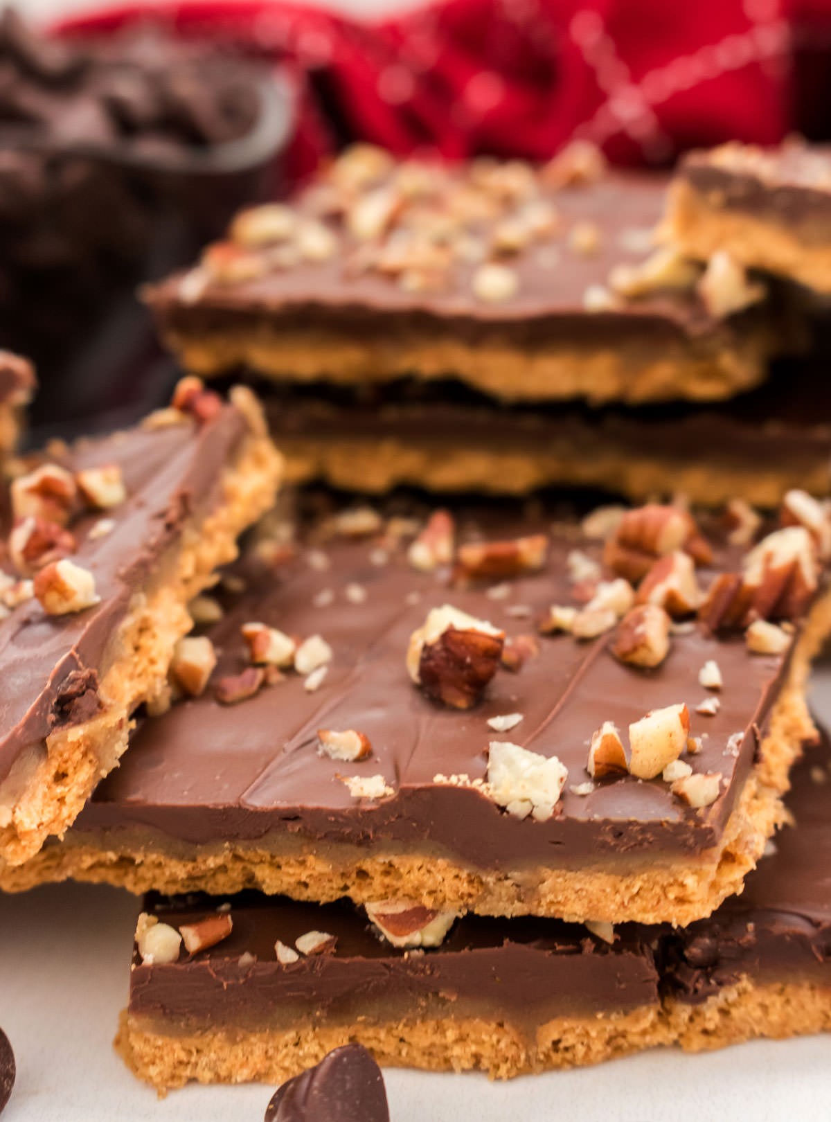 Closeup on a stack of Graham Cracker Toffee pieces arranged on a white surface in front of a red kitchen towel.