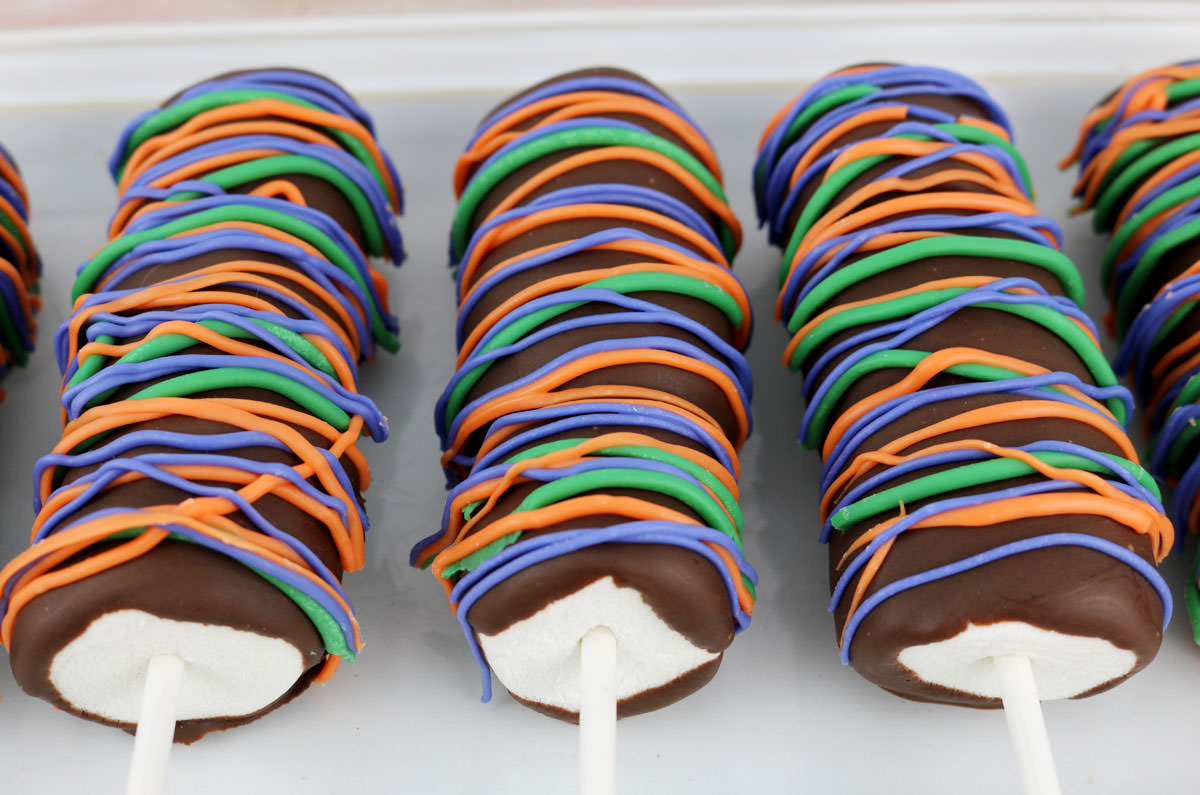 Closeup of three Halloween Marshmallow Pops laying on a white serving platter.