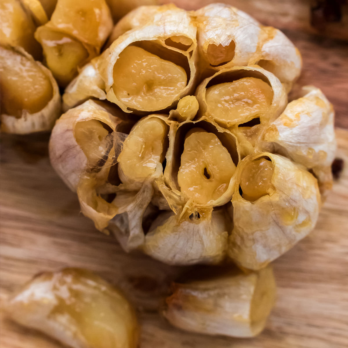 Closeup overhead shot of a roasted head of garlic sitting on a cutting board.