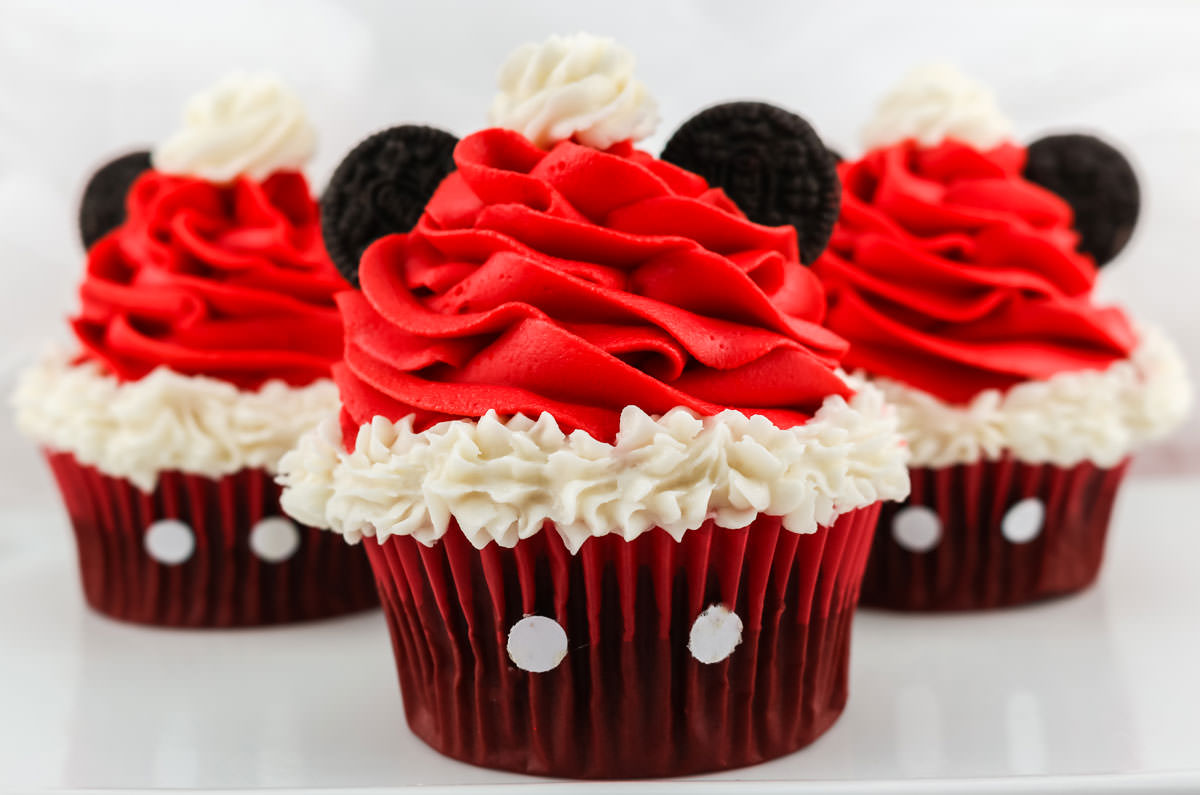 Closeup on three Mickey Mouse Santa Hat Cupcakes sitting on a white table.