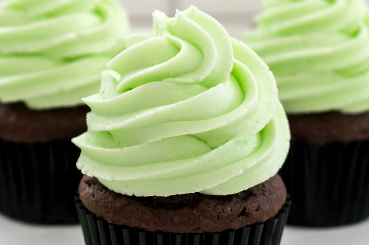 Closeup on three chocolate cupcakes frosted with The Best Mint Frosting.