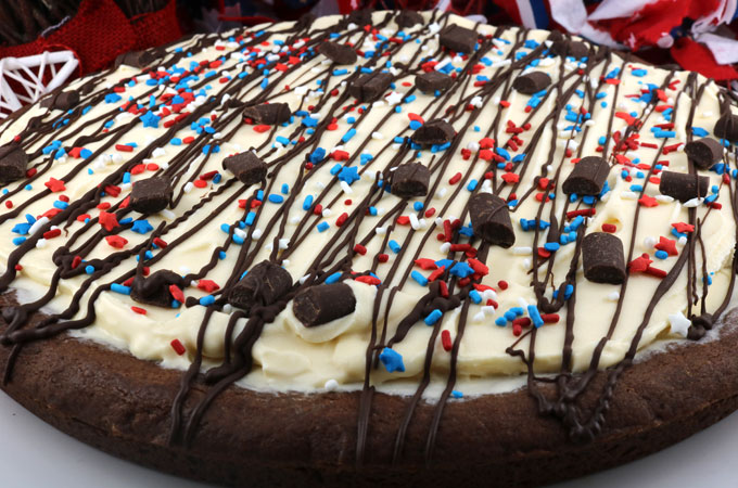 Patriotic Ice Cream Cookie Pizza - a fun and yummy dessert pizza made with chocolate cookie and vanilla ice cream topped with gorgeous red white and blue sprinkles. This Fourth of July dessert will wow the guests at your 4th of July party. Pin this 4th of July treat for later and follow us for more great 4th of July Food ideas. #4thofJuly #fourthofjuly #4thofJulyTreats #4thofJulyDesserts #4thofJulyFoodIdeas