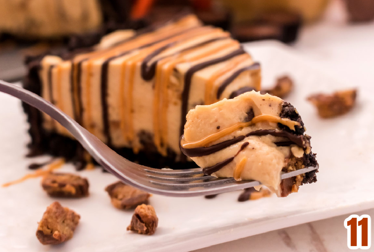 Closeup on a fork with a bite of Peanut Butter Cheesecake hovering in front of the rest of the piece of cheesecake.