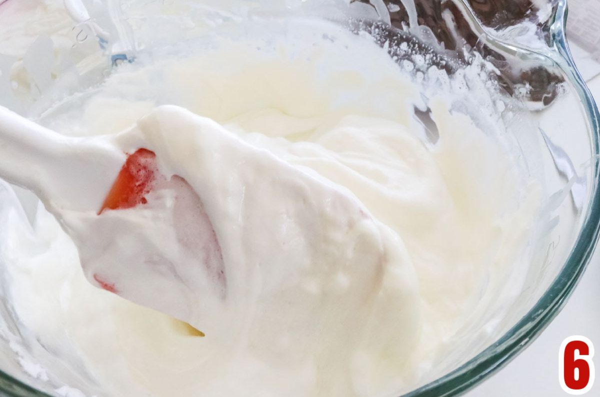 Closeup on a glass mixing bowl with the Peppermint Marshmallow filling and a red and white spatula.