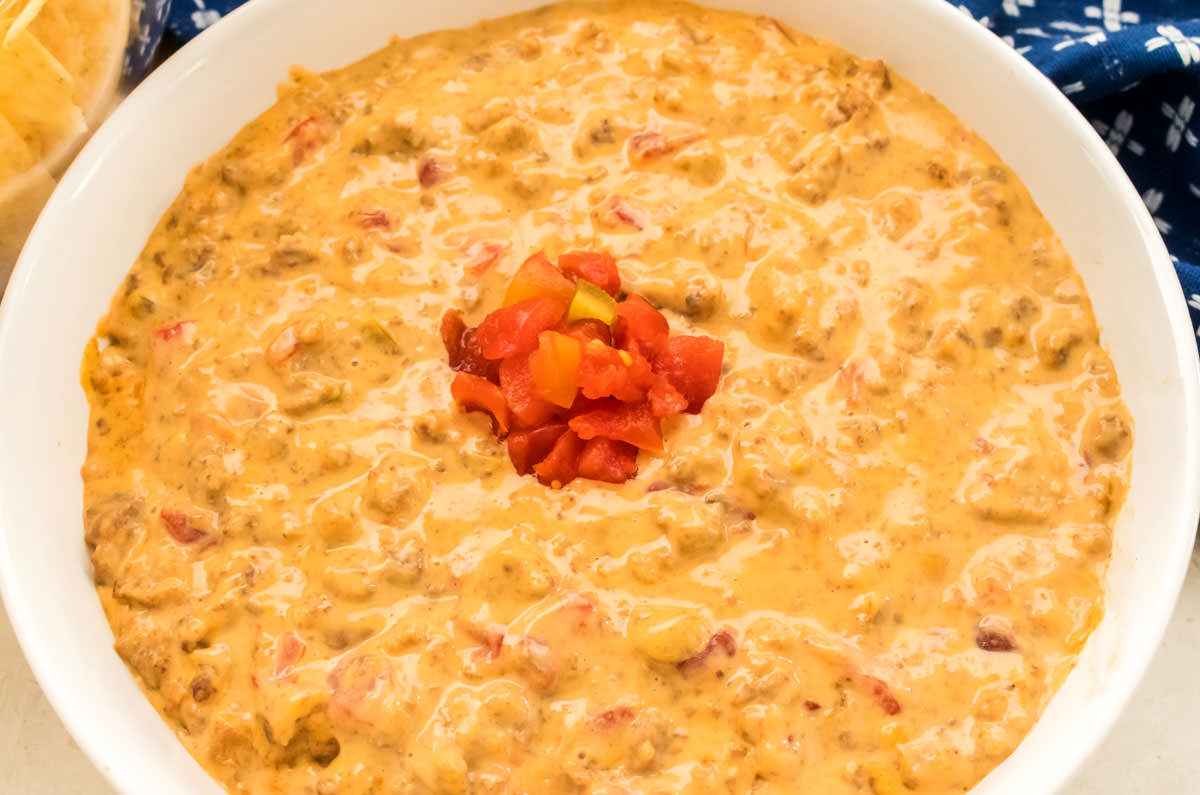 Closeup on a bowl of Rotel Dip in a white bowl with a dollop of Ro-Tel Tomatoes in the center of the bowl.