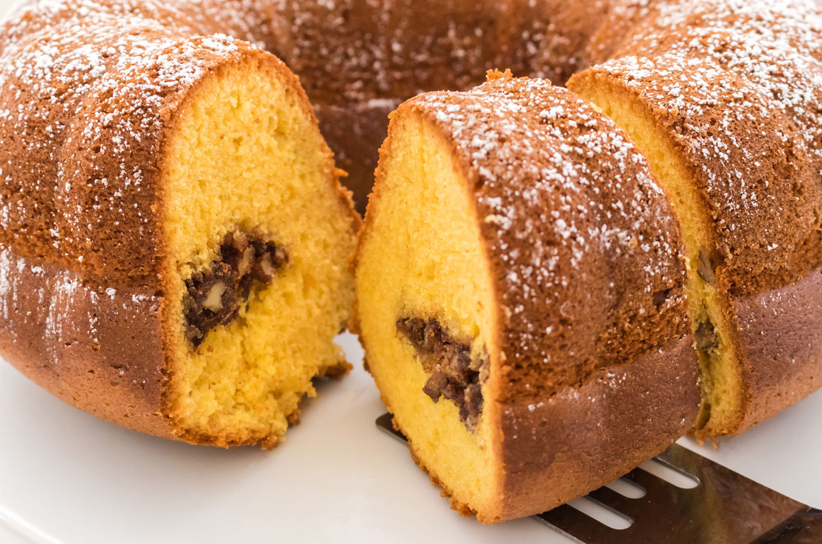 Closeup on a Christmas Morning Coffee Cake sitting on a white cake stand with a spatula pulling out a single piece of the cake