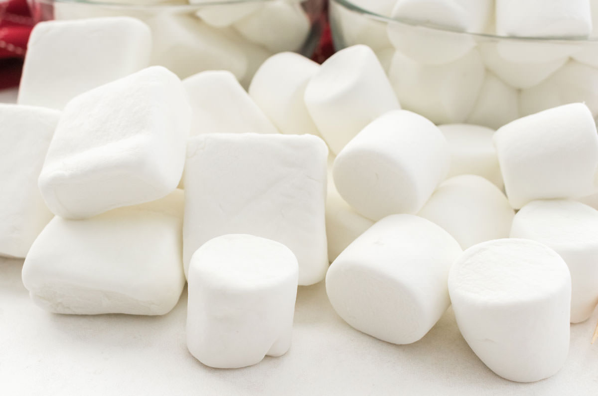 Two types of marshmallows laying in a pile on a white table.