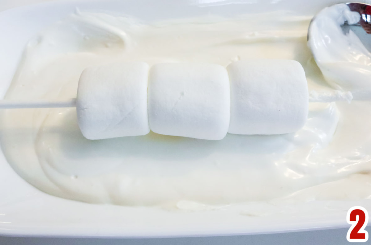 Marshmallow pop sitting in a pool of melted white chocolate.