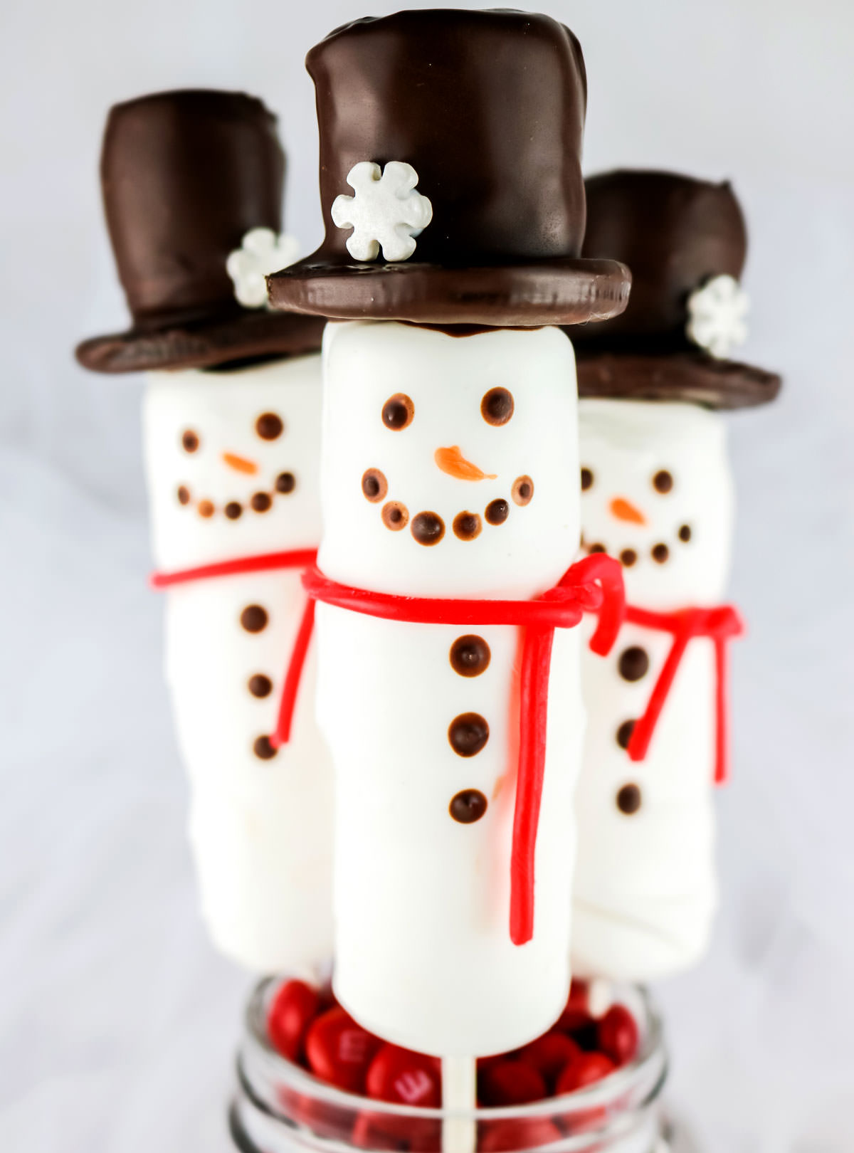 Closeup on three Snowman Marshmallow Pops sticking out of a Mason Jar.