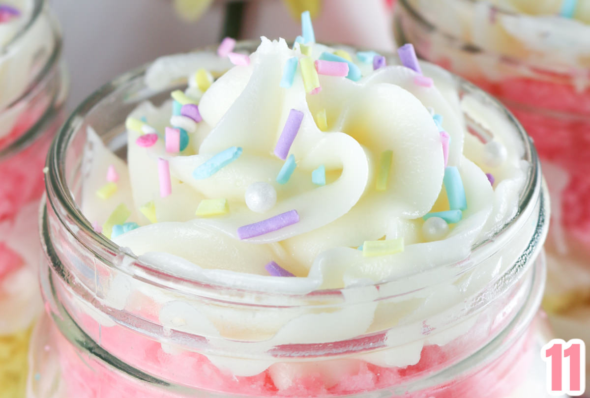 Close up on the buttercream frosting swirl with pastel sprinkles on the top of a Springtime Cupcake  in a Jar.