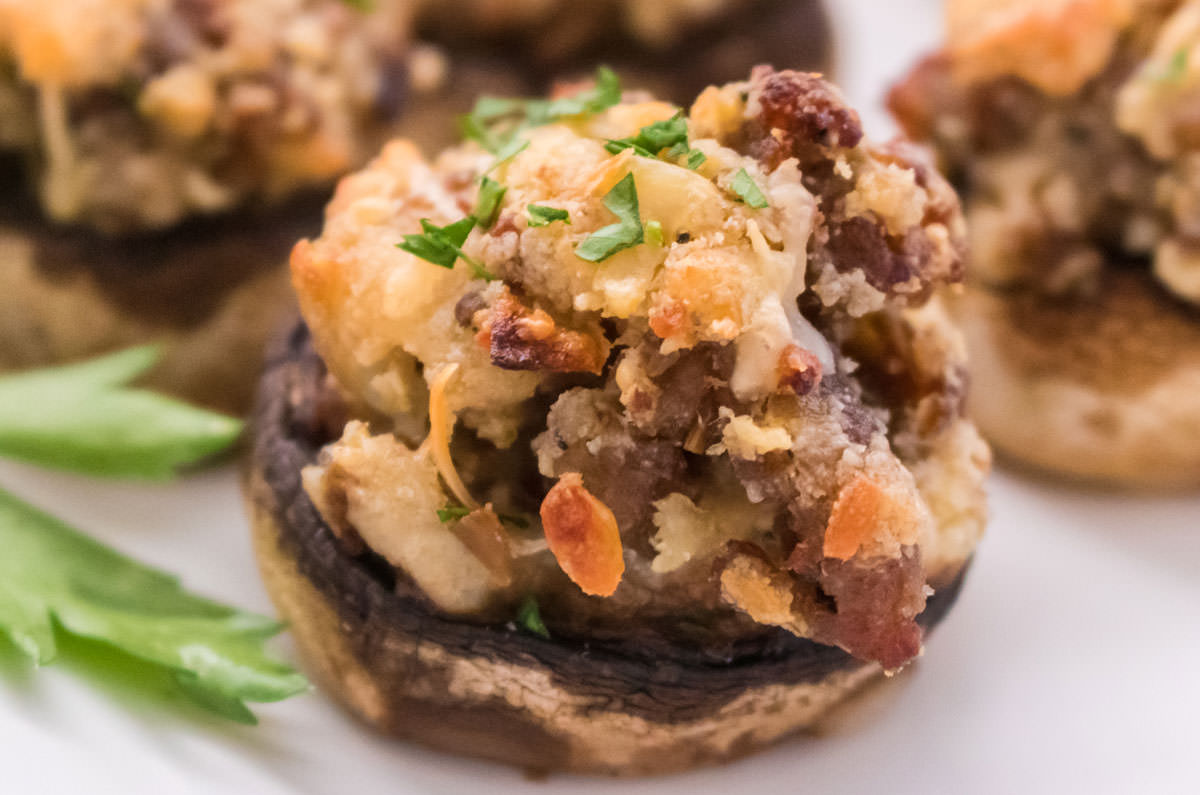 Closeup of a Stuffed Mushroom sitting on a white serving platter.