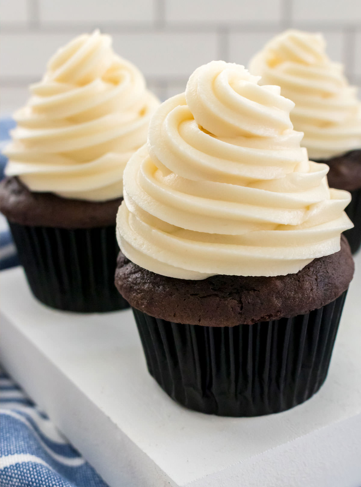 Closeup on three chocolate cupcakes topped with The Best Cream Cheese Frosting.