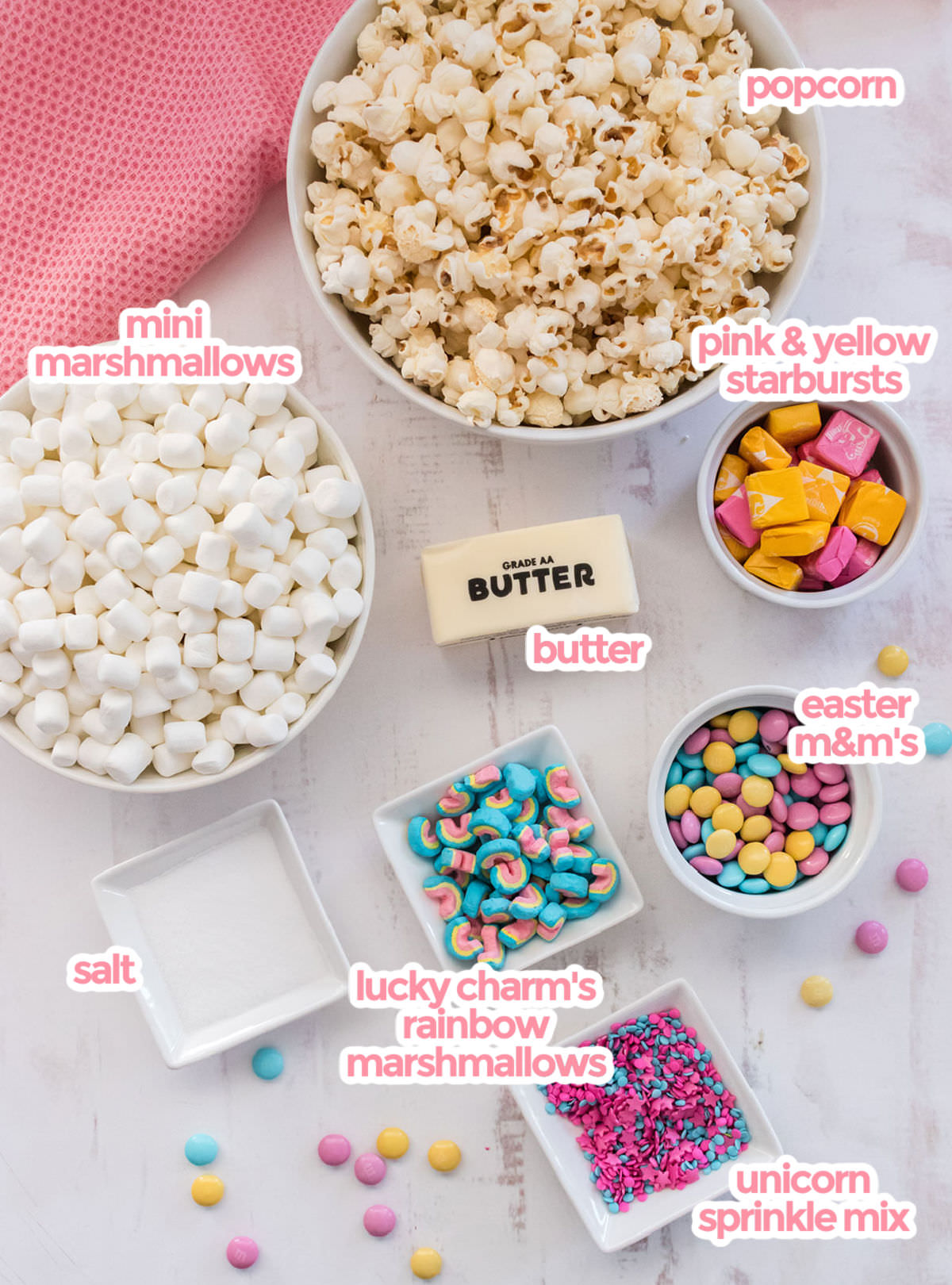 All the ingredients needs to make Unicorn Popcorn including popcorn,  marshmallows, starburst candies, butter, M&M's, sprinkles, rainbow marshmallows and salt. 