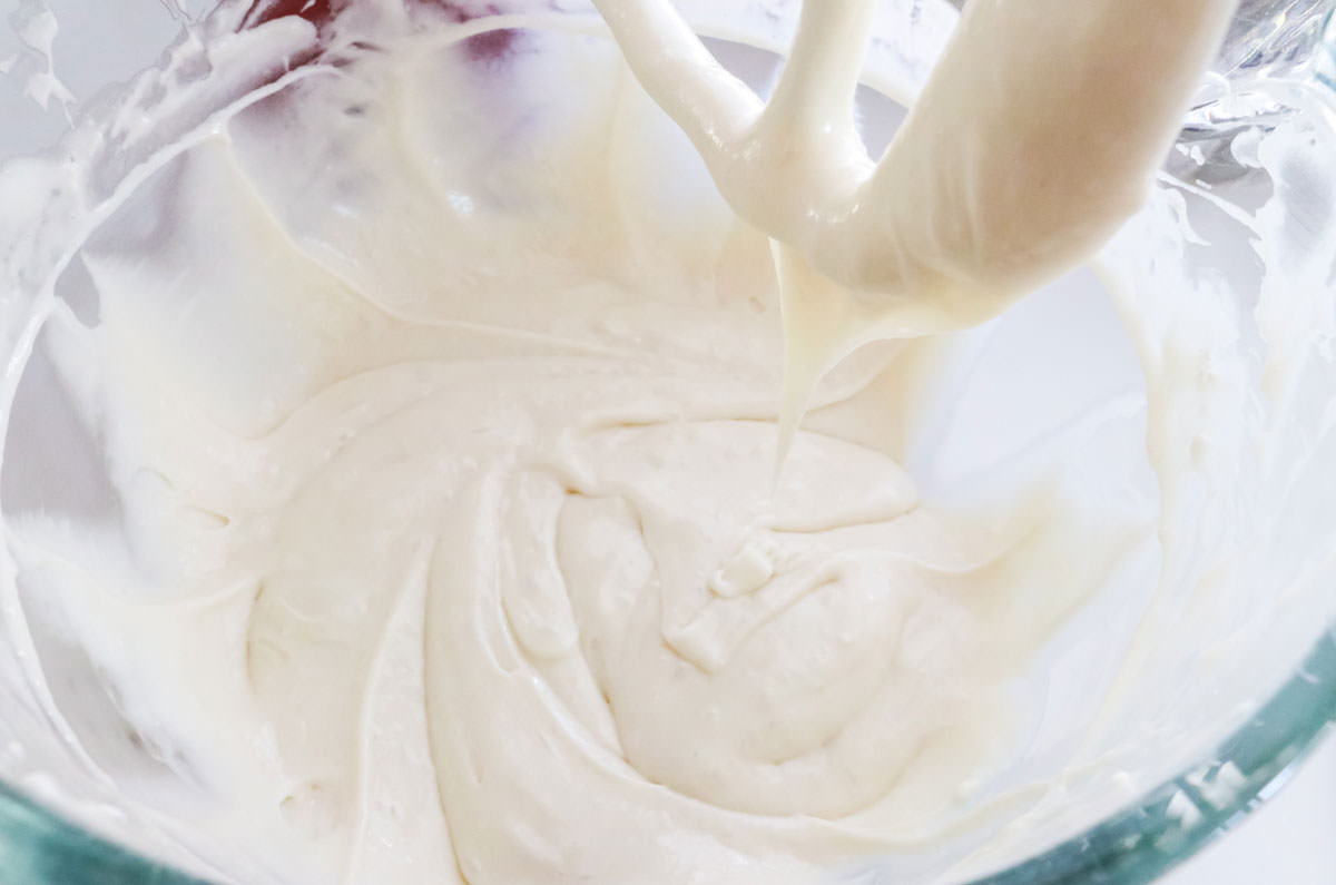 Closeup on a clear mixing bowl filled with white cake batter.