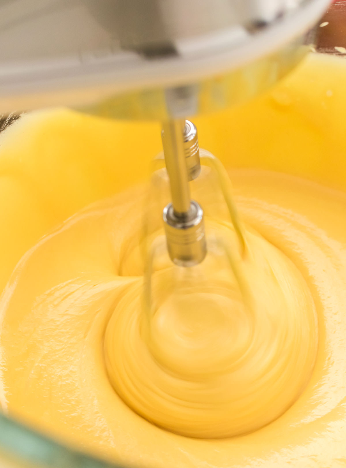 A clear mixing bowl filled with yellow cake batter.